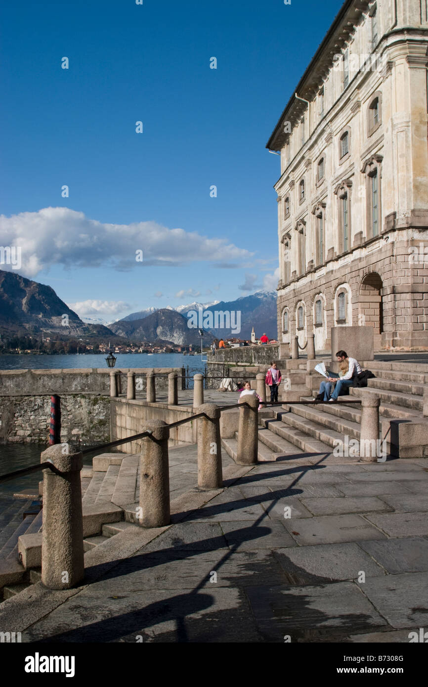 Palazzo Borromeo sur Isola Bella avec vue sur les Alpes et de l'Isola dei pescatori, Lac Majeur, Italie. Couple assis sur les marches. Banque D'Images