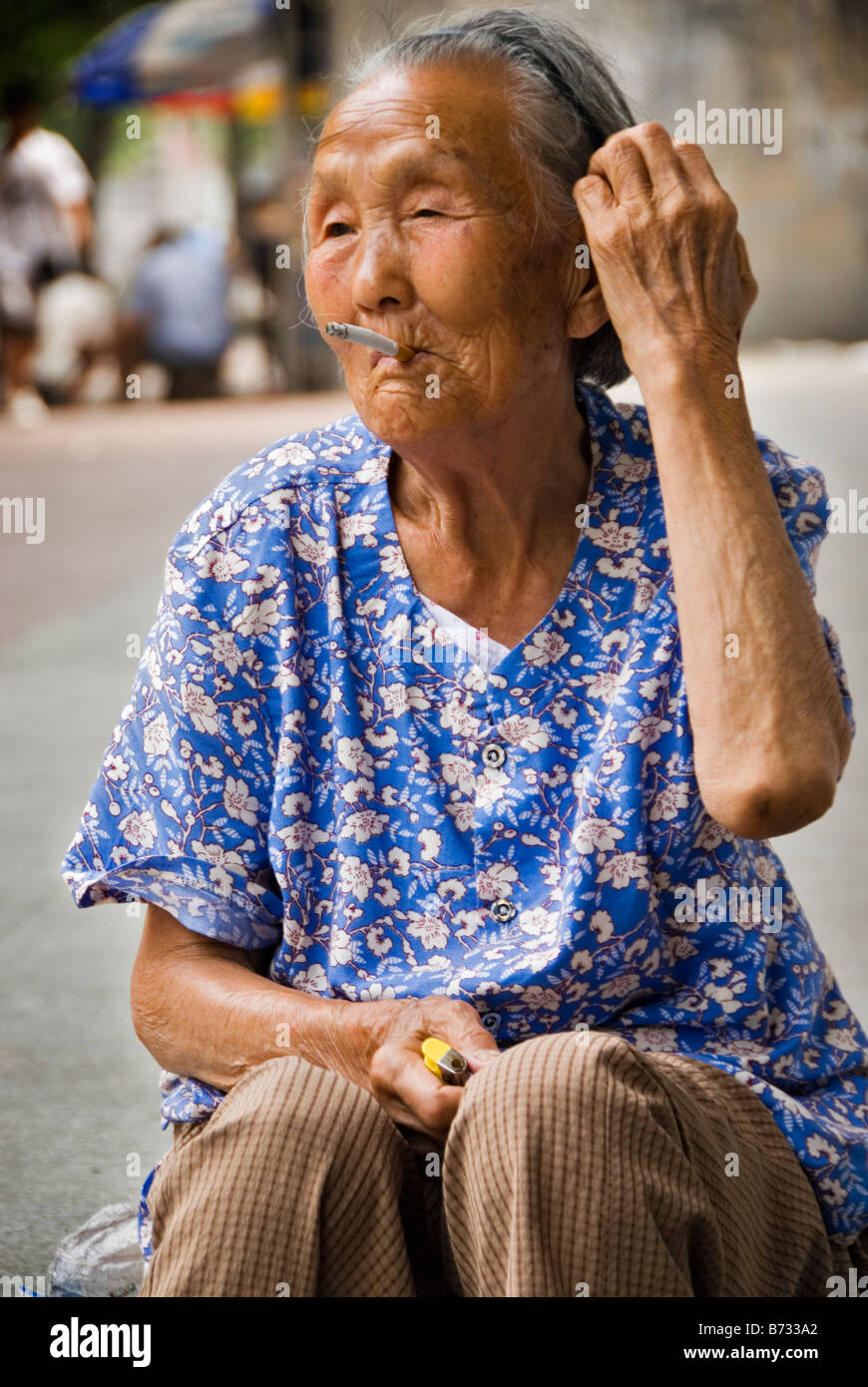 Chinesse vieille femme fumer une cigarrette dans la rue Xian Chine Shaanxi Banque D'Images