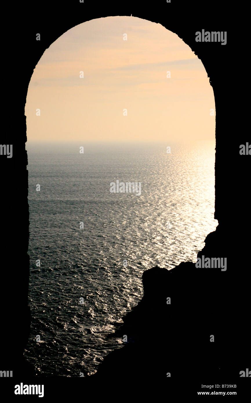 Voir au coucher du soleil sur une mer brumeuse d'une maison à l'abandon du moteur de Cornouailles perché sur une falaise Banque D'Images