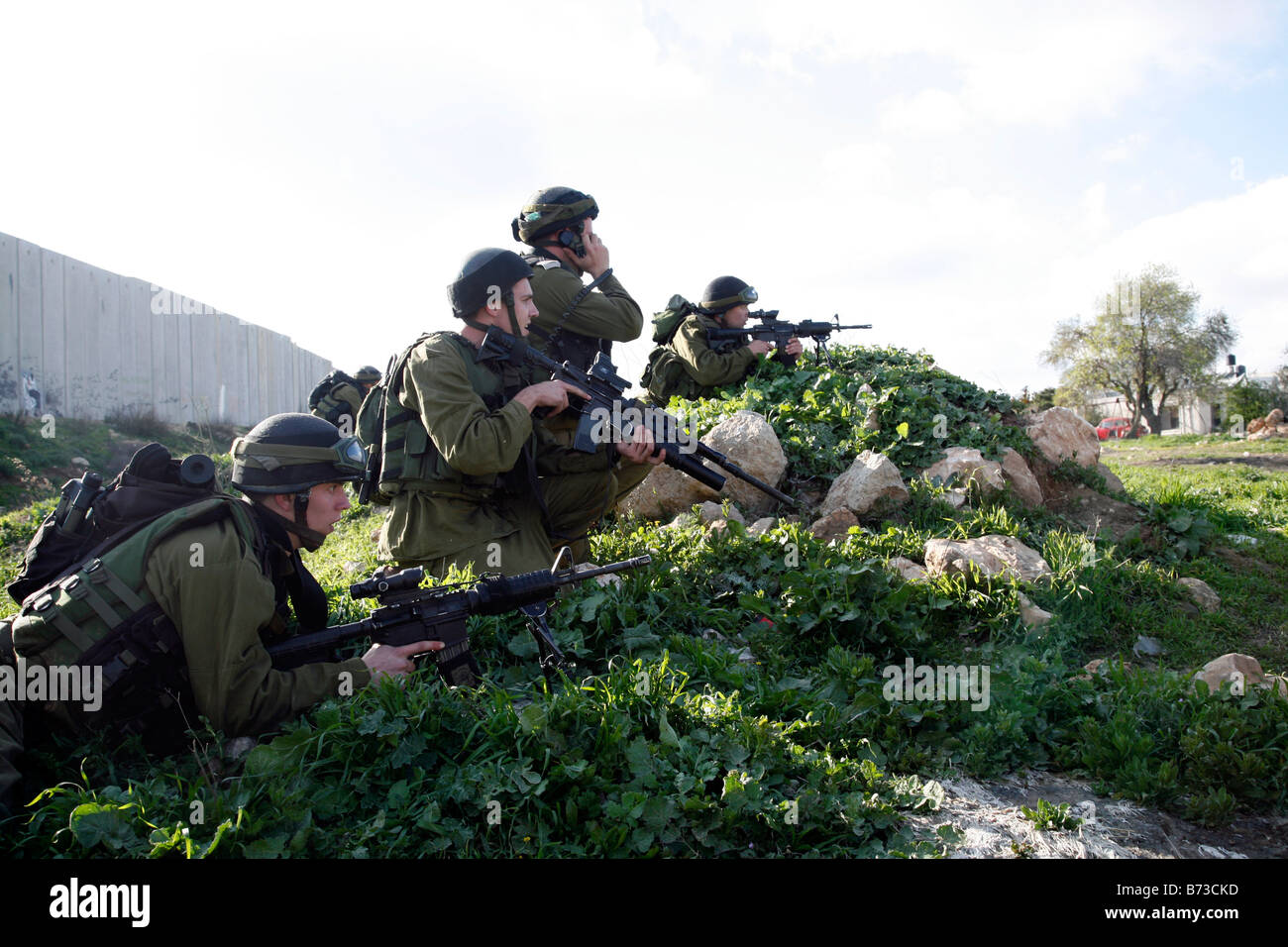 Des soldats israéliens se préparent à tirer des balles en caoutchouc sur les lanceurs de pierres palestiniens près de la barrière de séparation en Cisjordanie. Banque D'Images