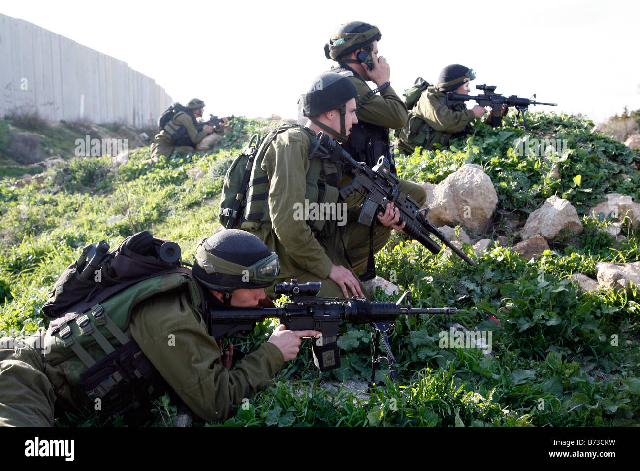 Des soldats israéliens se préparent à tirer des balles en caoutchouc sur les lanceurs de pierres palestiniens près de la barrière de séparation en Cisjordanie. Banque D'Images