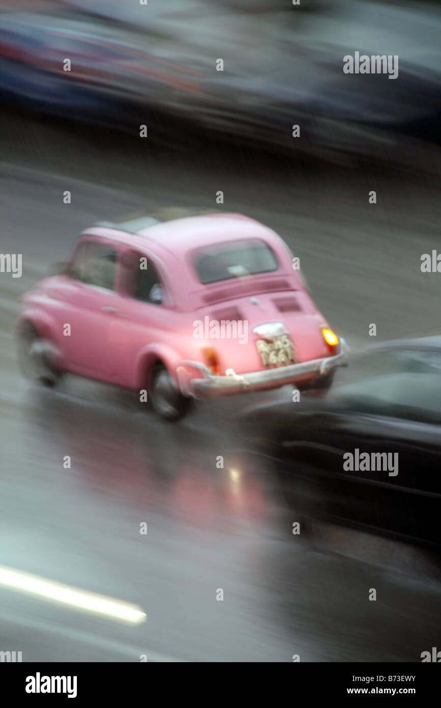 Fiat 500 rose rapide voiture conduire dans de fortes pluies à Rome Italie Banque D'Images