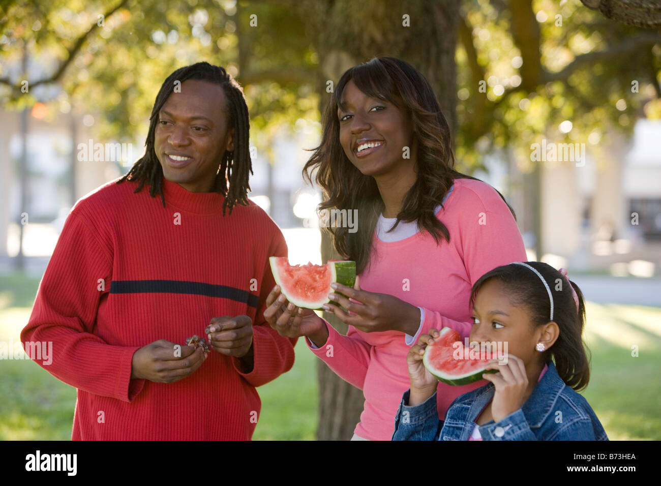 Young African American family eating watermelon in park Banque D'Images