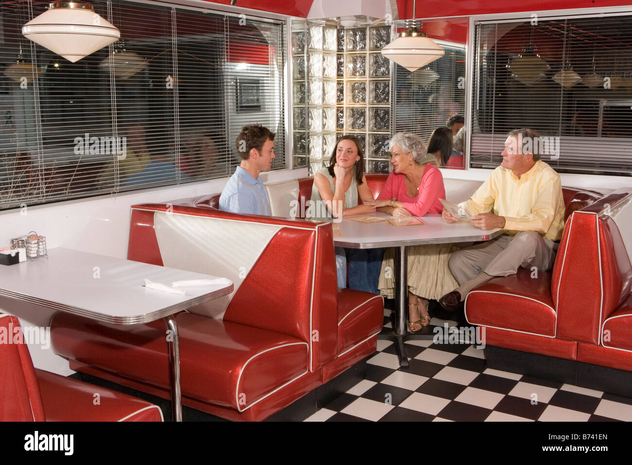 Family sitting in corner stand de parler à l'ancienne salle à manger Banque D'Images