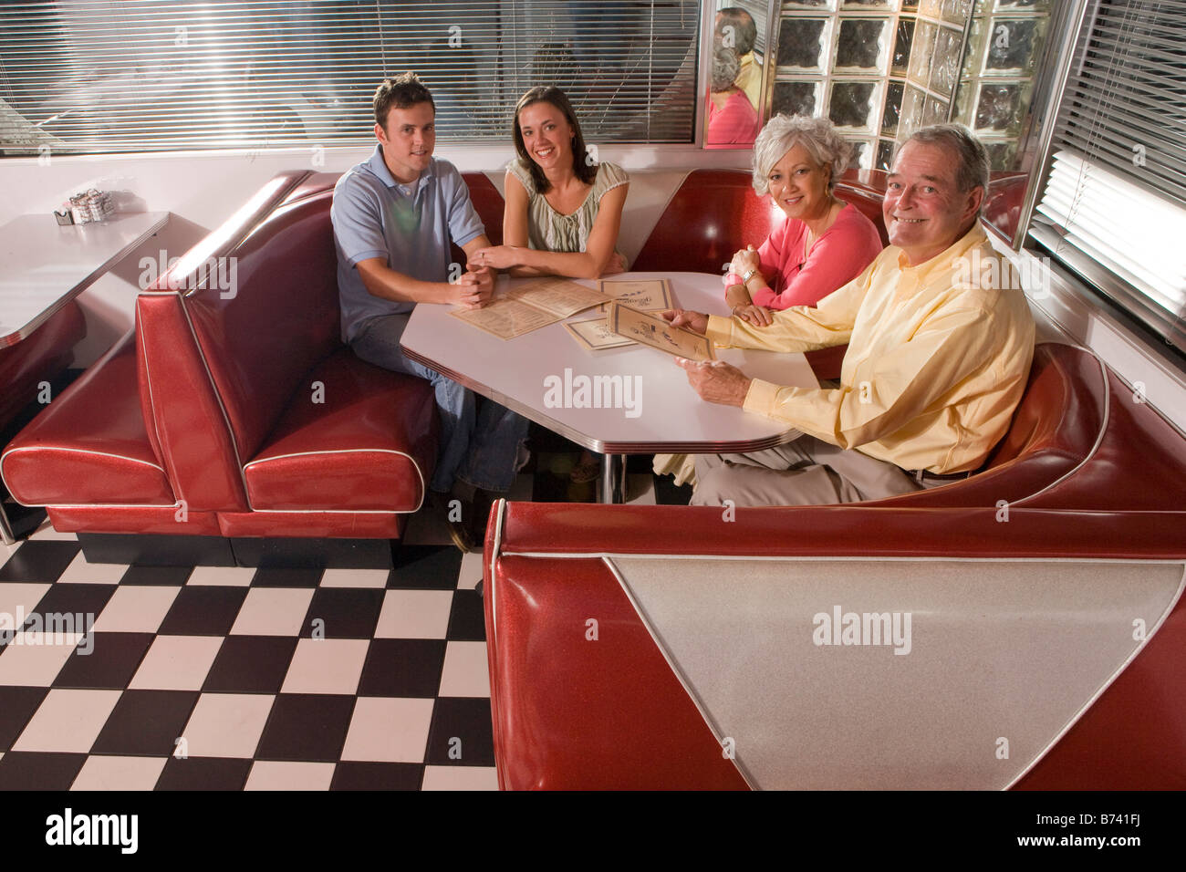 Jeune couple avec les parents assis sur le stand de vieux diner Banque D'Images