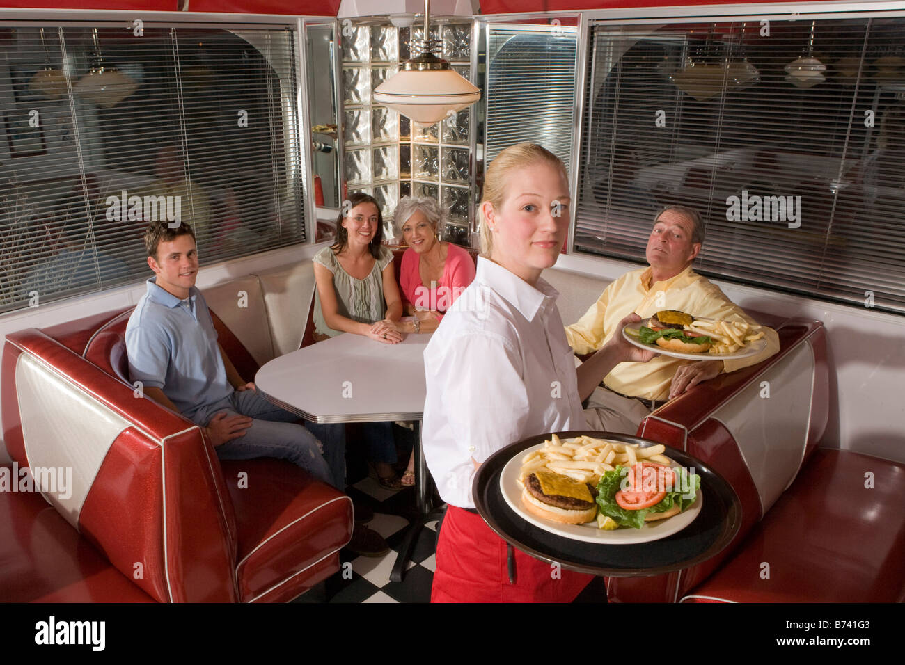 Waitress serving diners les hamburgers et les frites dans un restaurant Banque D'Images