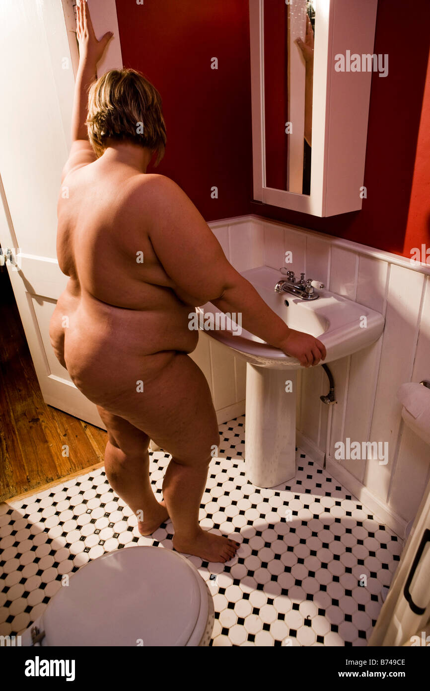 L'excès de femme nue à la recherche de miroir de salle de bains Photo Stock  - Alamy