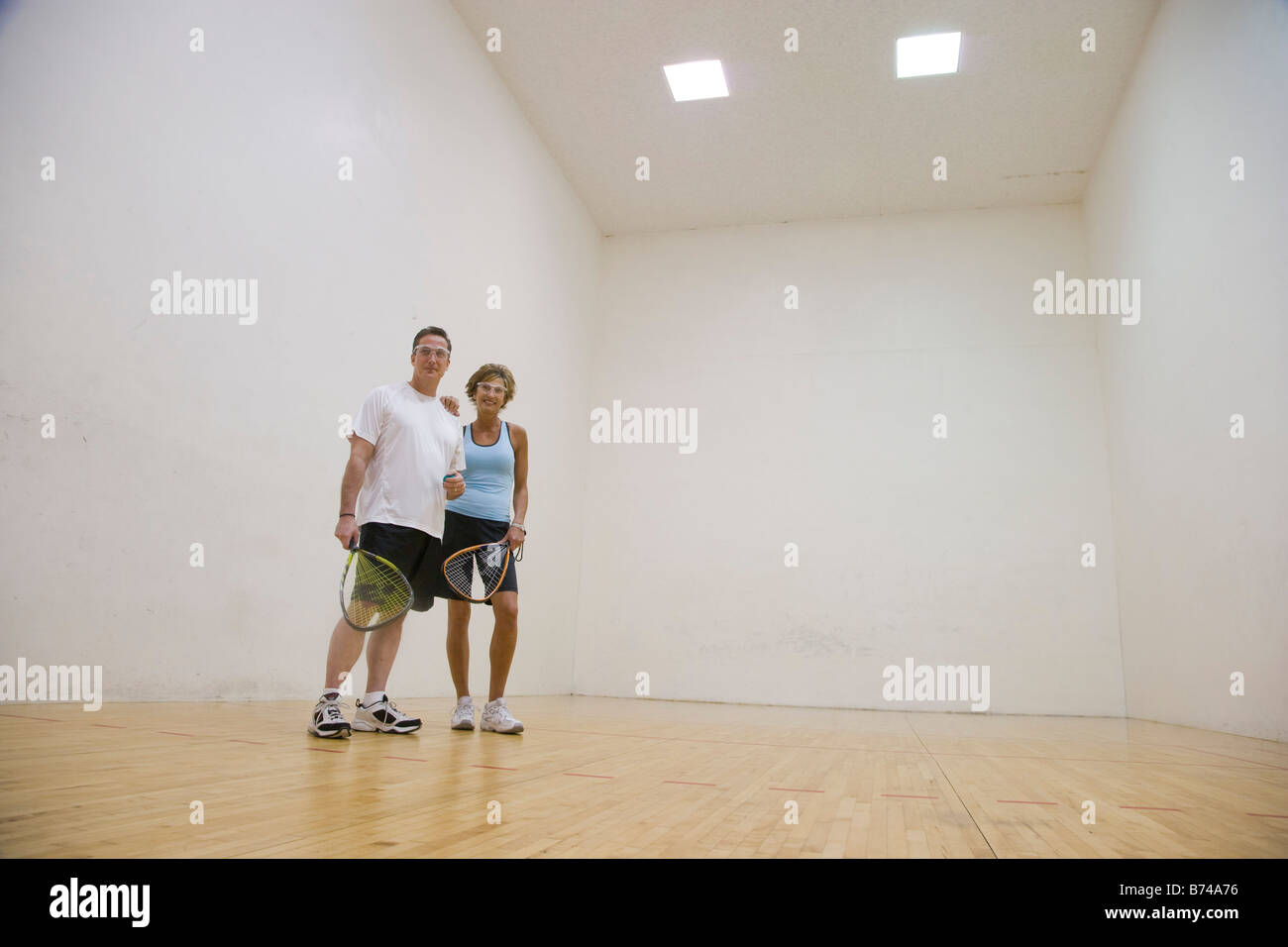 Middle-aged couple jouant dans une piscine de racquetball Banque D'Images