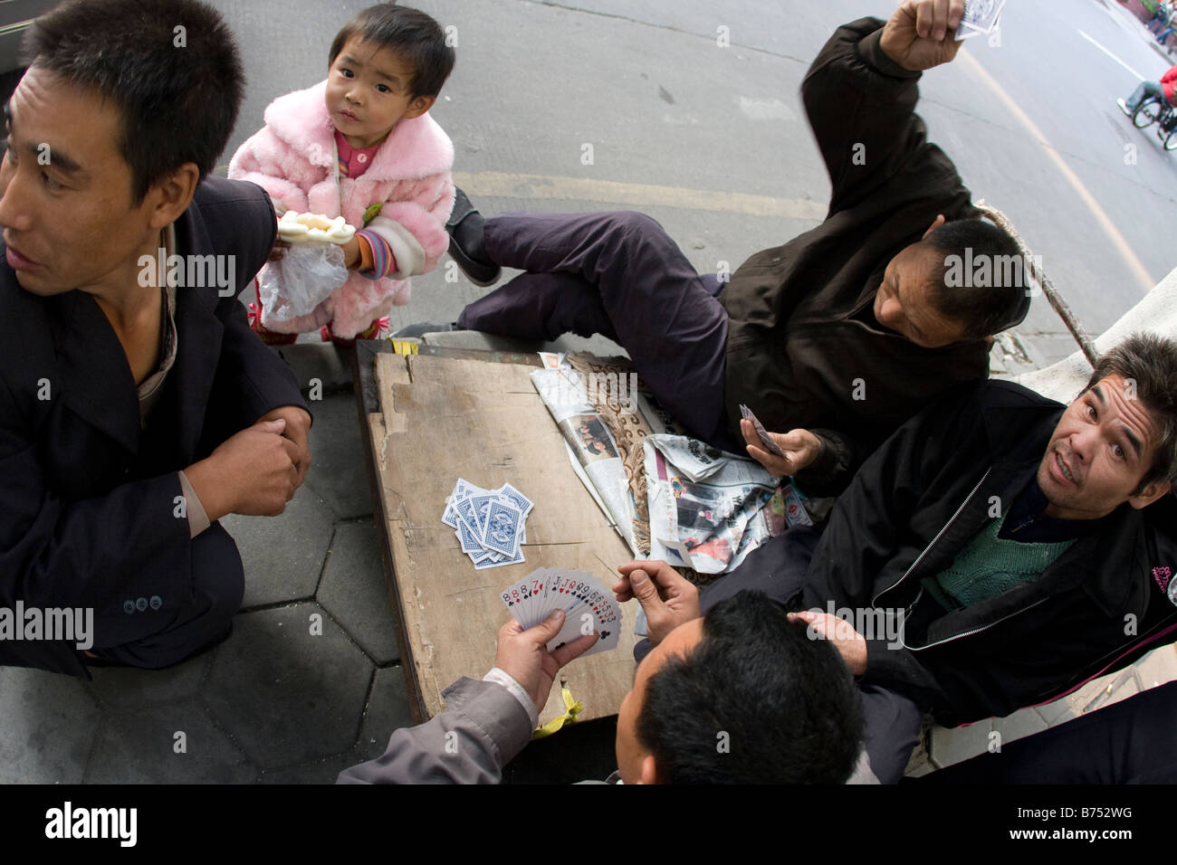 Groupe d'wokers de rue jouer poker chinois avec petite fille dans les rues de la communauté de classe supérieure Banque D'Images