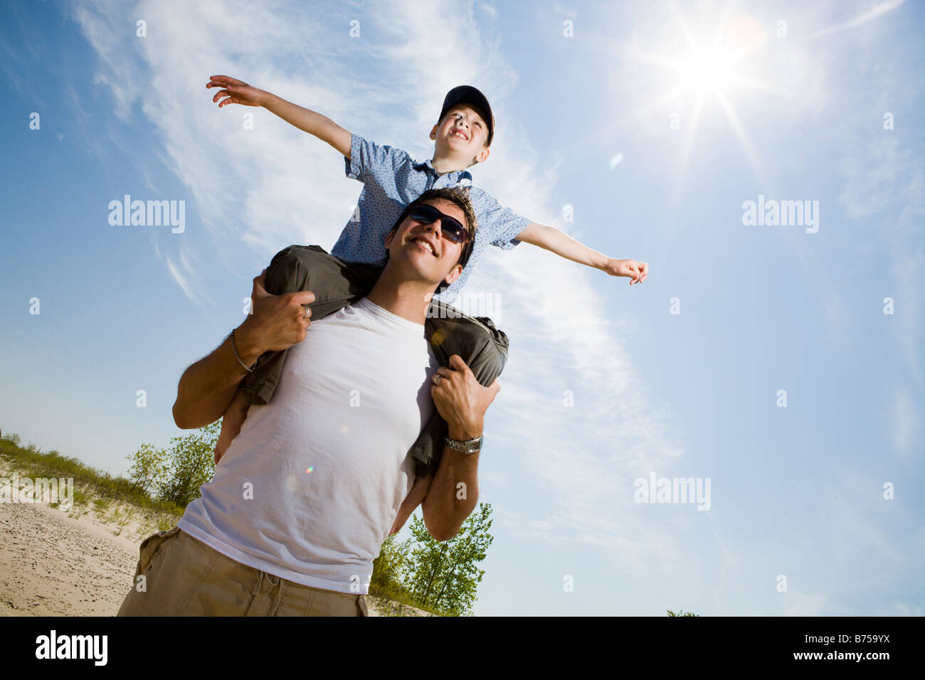 Low angle view avec sun flare de man avec boy (7) sur ses épaules, le parc provincial de Grand Beach, Manitoba, Canada Banque D'Images