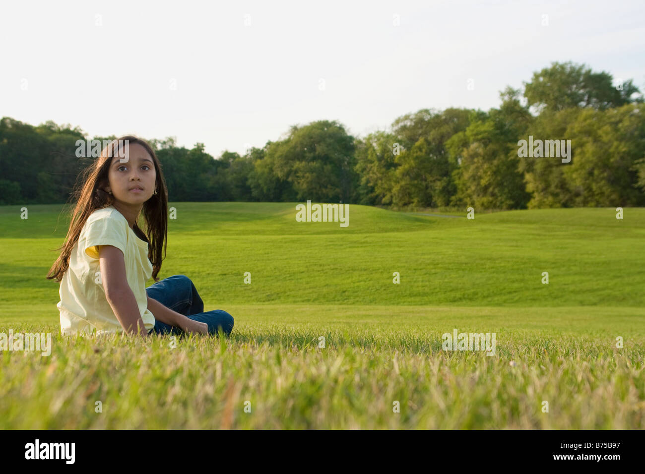 Fillette de huit ans assis sur l'herbe en Park, Winnipeg, Canada Banque D'Images