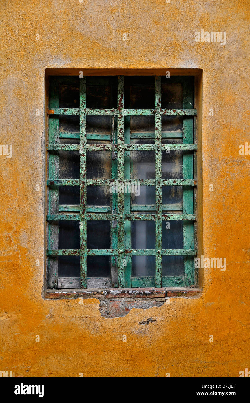 Rustique et lumineuse jaune très coloré de mur avec une fenêtre et barres bleues. Tout à fait de la Méditerranée. Banque D'Images