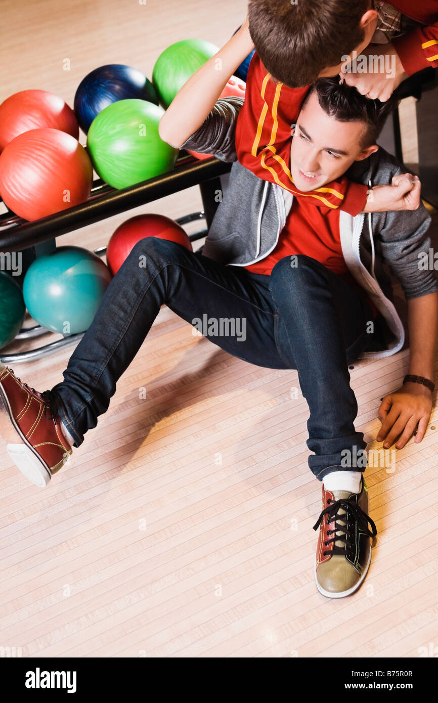 Portrait d'un jeune homme agrippant un autre jeune homme dans le cou d'un bowling Banque D'Images