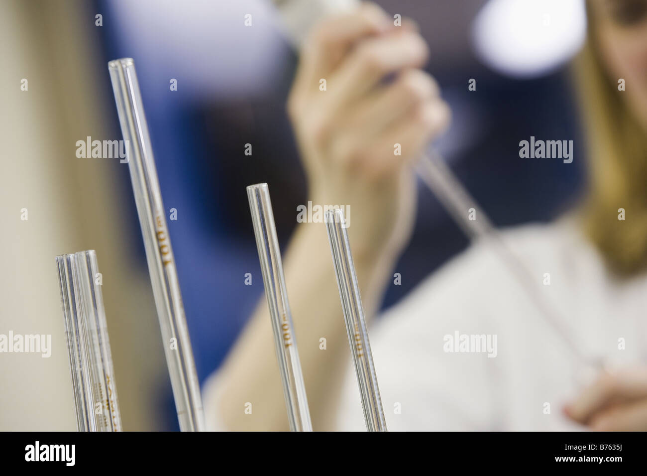 Close-up de 4 pipettes volumétriques avec un scientifique dans l'arrière-plan de pipetage Banque D'Images