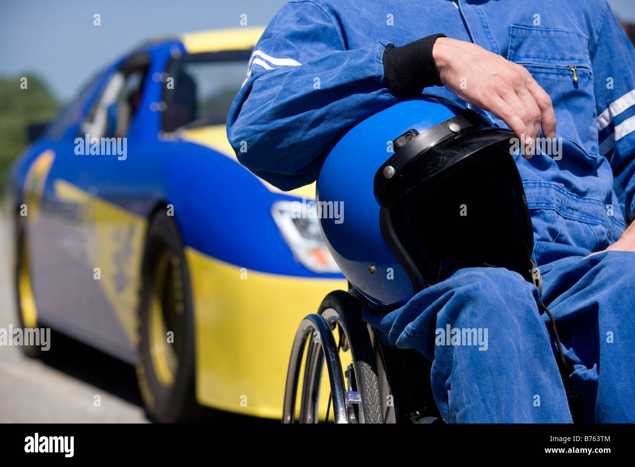 Pilote de voiture de course d'invalidité, mid section, car en arrière-plan Banque D'Images