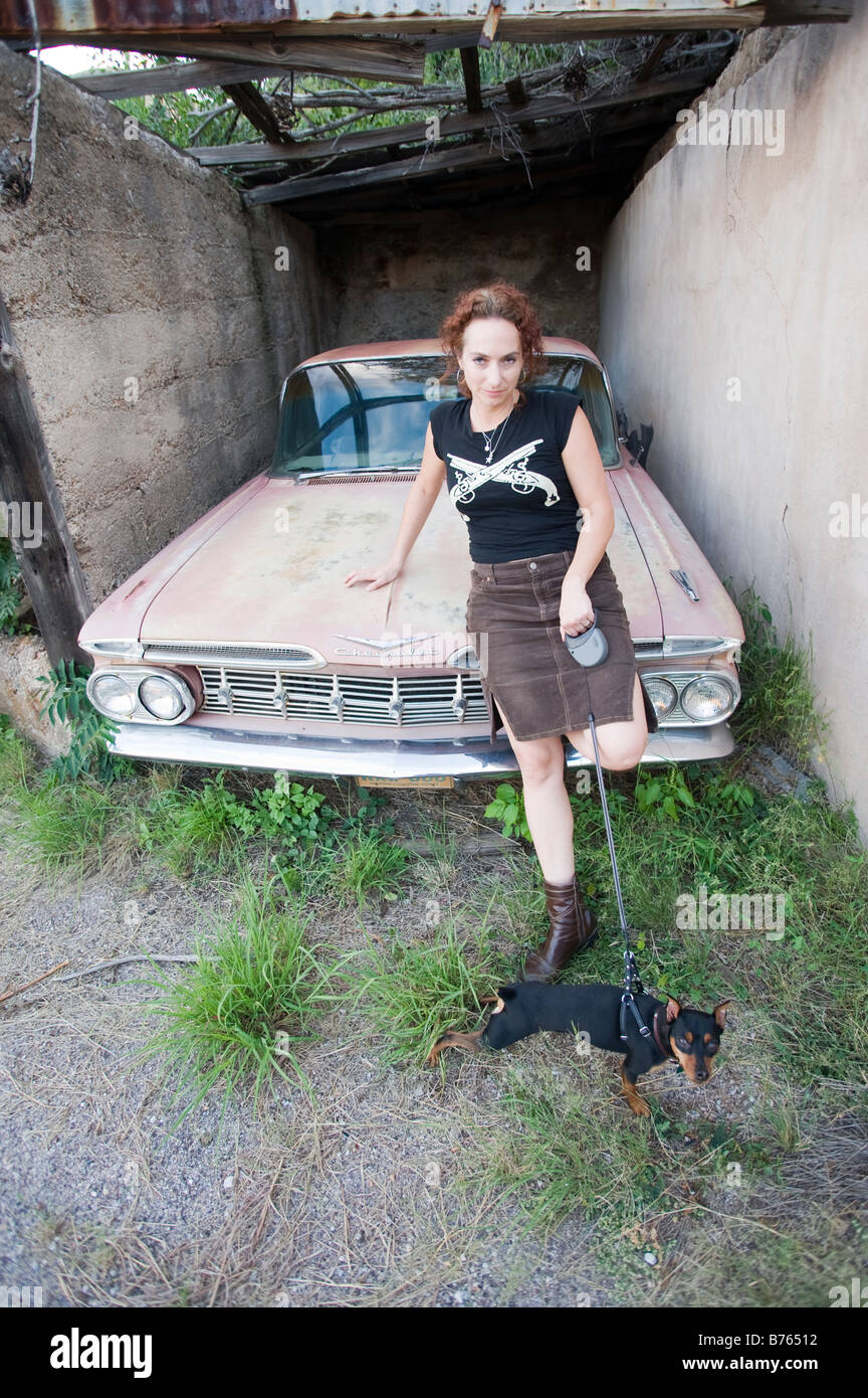 La femme pose contre une voiture classique avec son chien, une miniature pincher Bisbee, AZ Banque D'Images