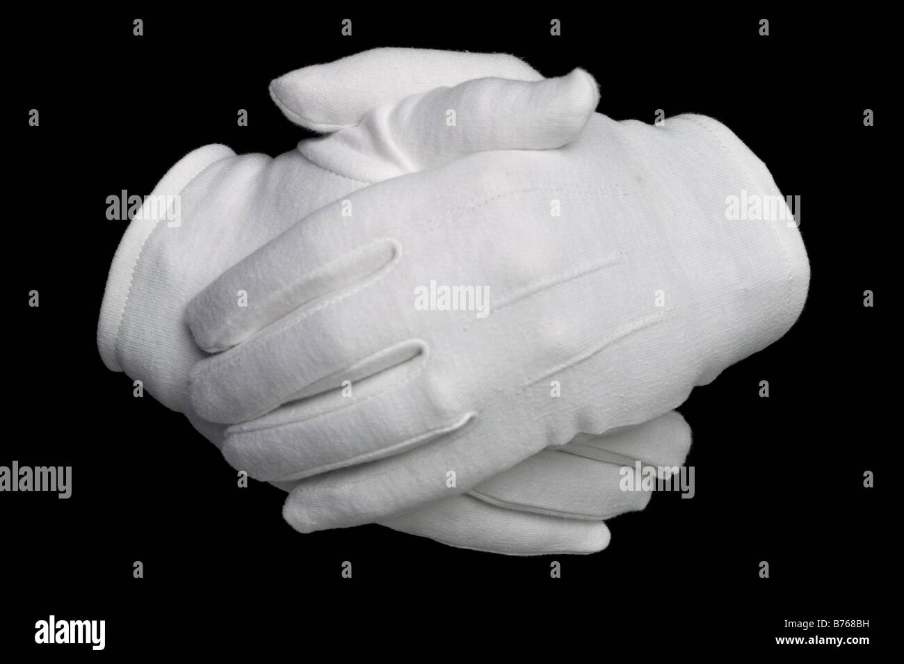 Mains dans des gants de coton blanc isolé sur fond noir Banque D'Images