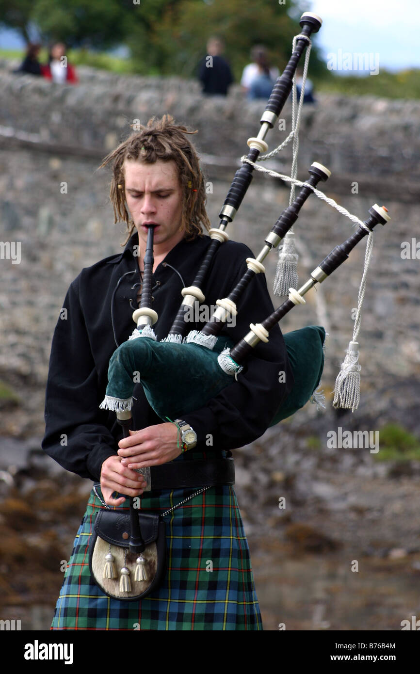 L'homme traditionnel en kilt, joueur de cornemuse dans les Highlands écossais avec cornemuses au château Eilean Donan Banque D'Images