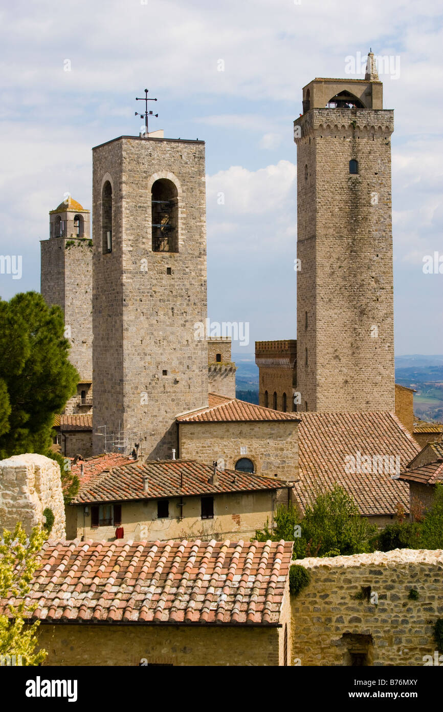 Trois clochers en pierre ancienne émergeant de toits en tuiles rouges dans la ville de San Gimignano Toscane Italie il Banque D'Images