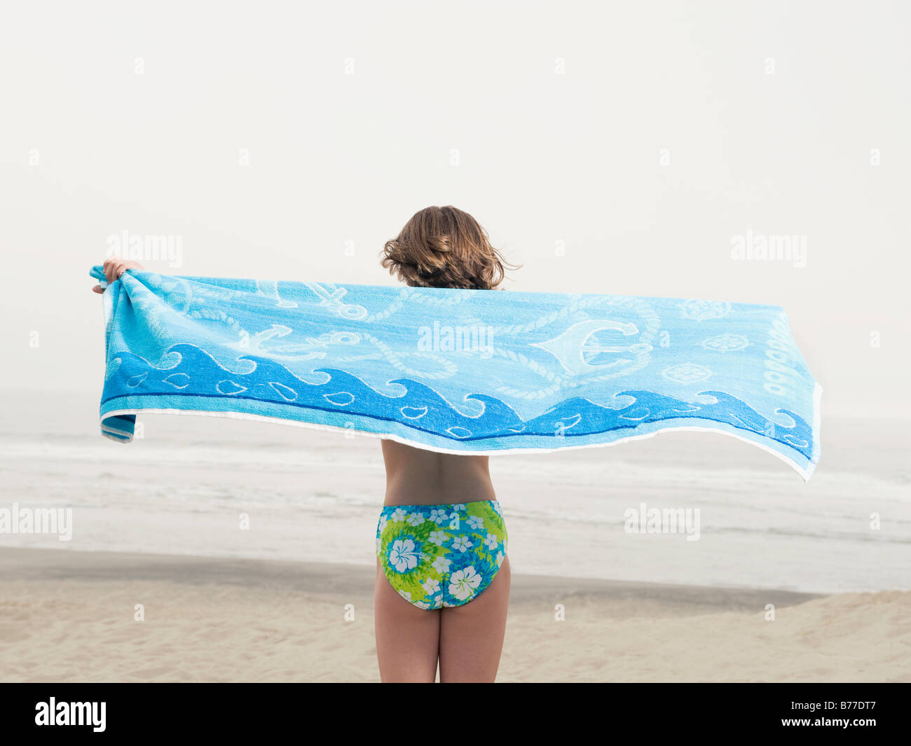 Girl holding towel on beach Banque D'Images