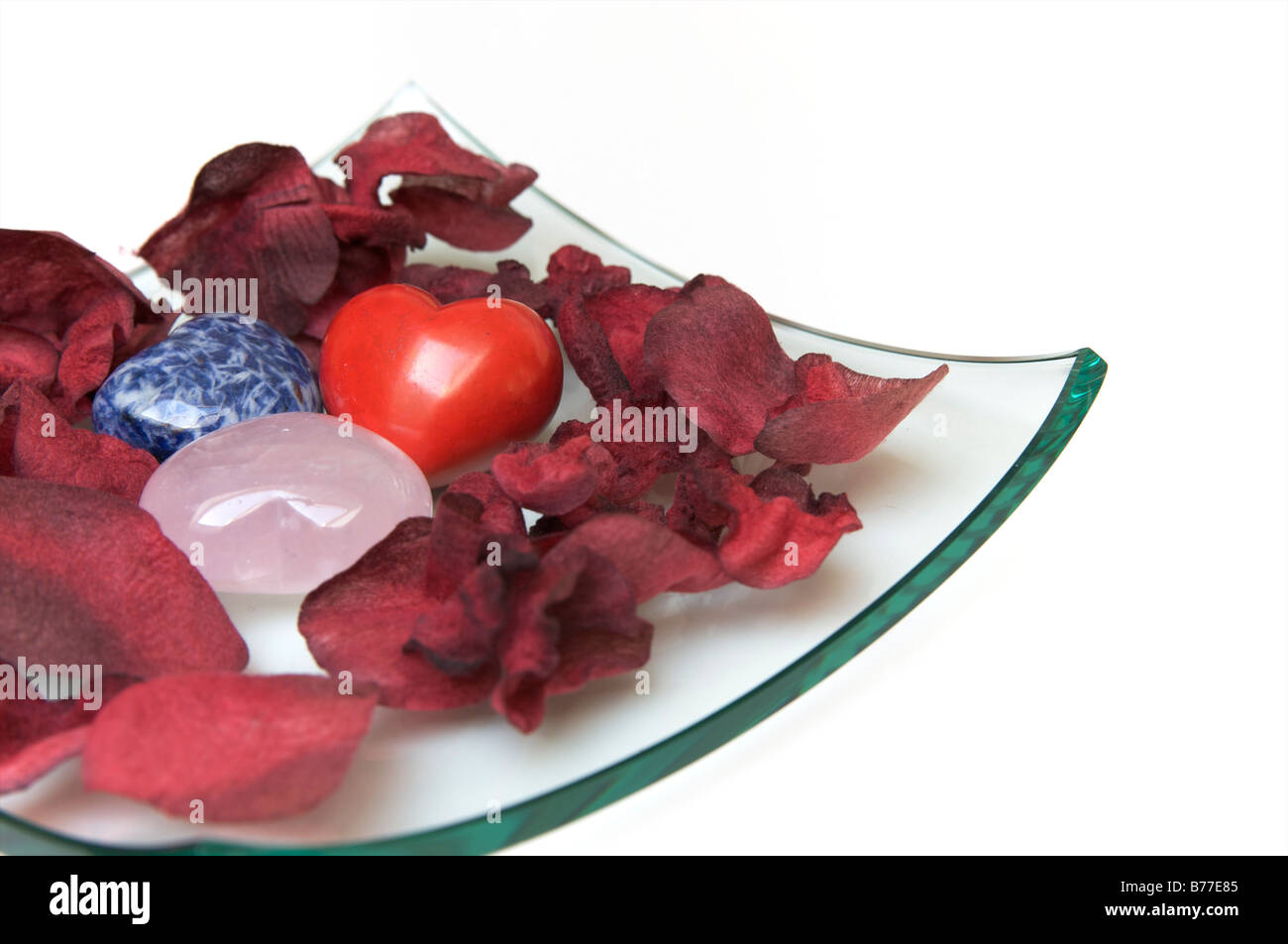 Bol en verre avec des coeurs de pierre et pétales de rose Banque D'Images