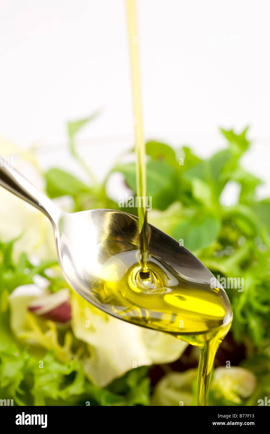 Verser l'huile d'olive dans la salade sur une cuillère Banque D'Images