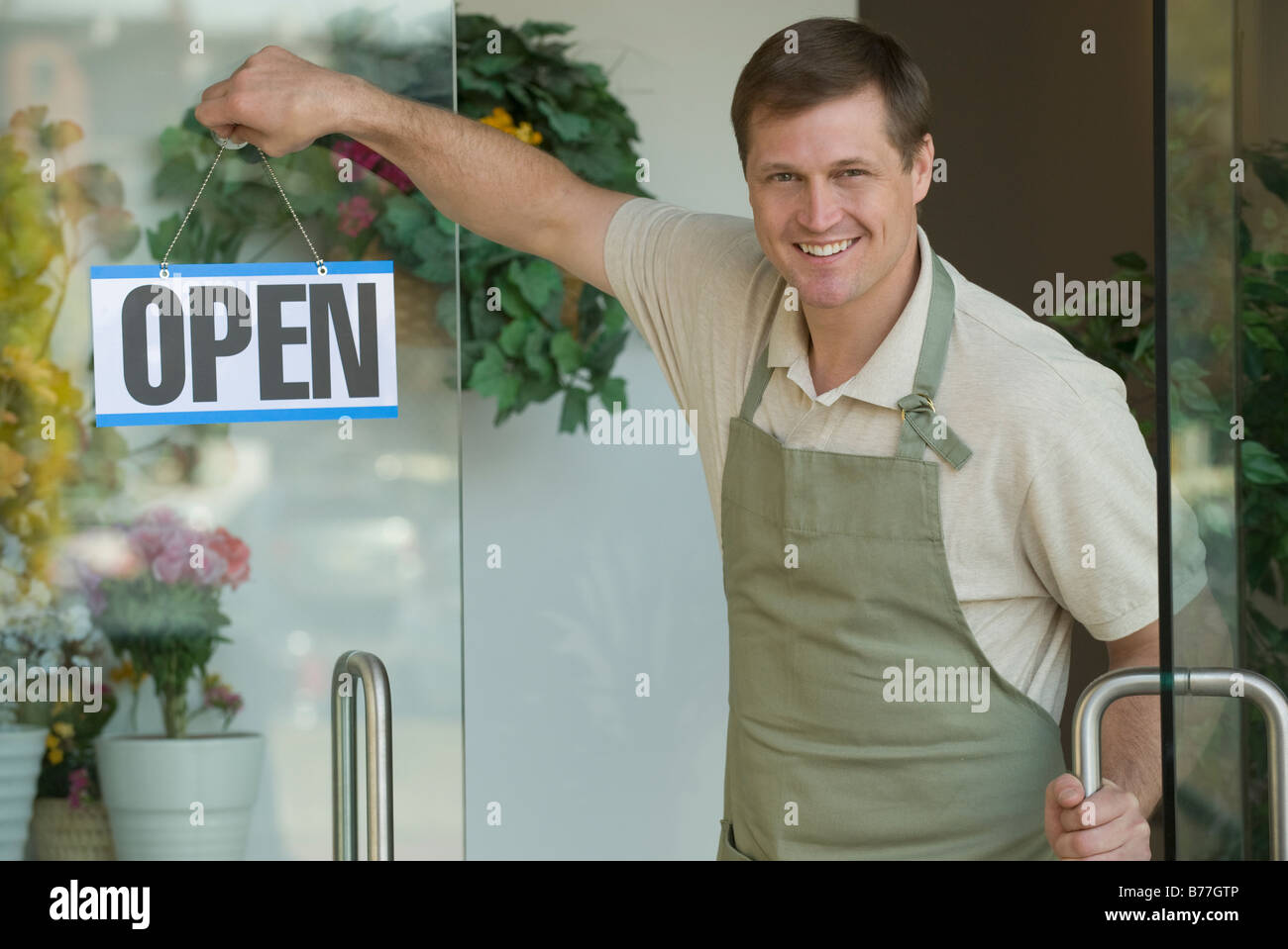 Man hanging open sign flower shop window Banque D'Images