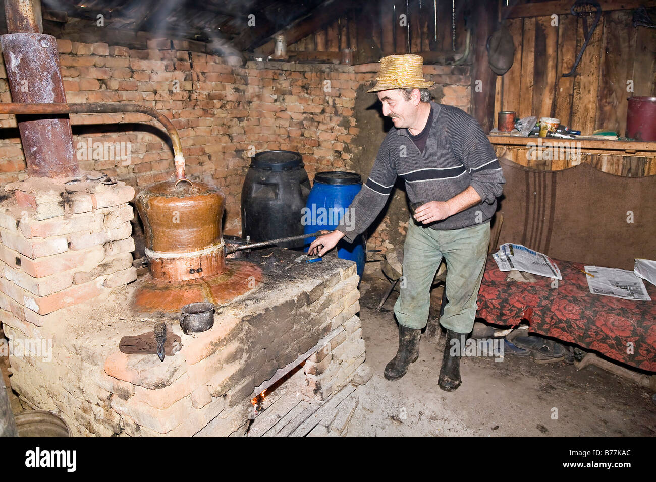 Homme avec un chapeau dans une distillerie de schnaps roumaine, Bezded, Salaj, Transylvanie, Roumanie, Europe Banque D'Images