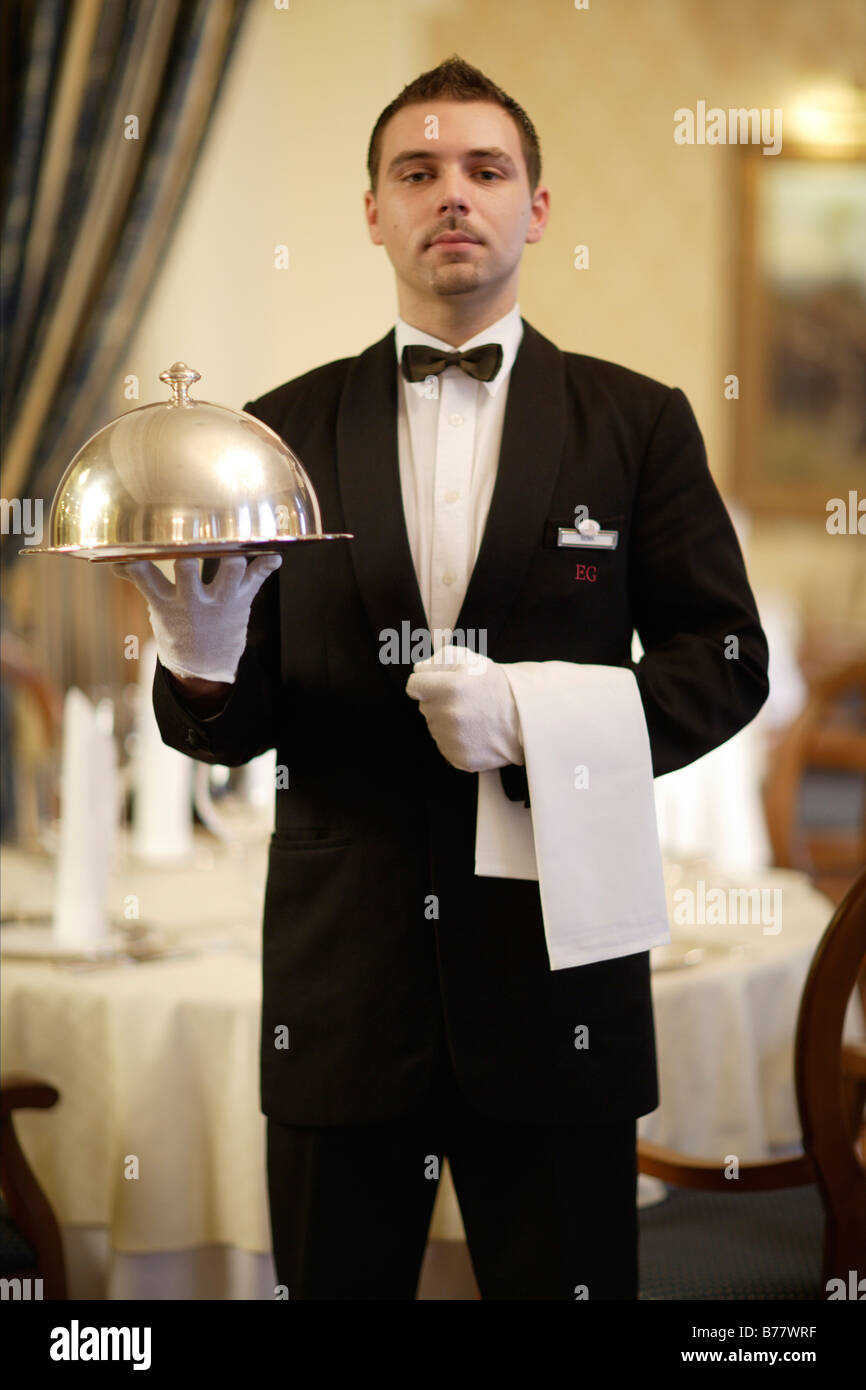 Waiter holding une cloche dans un restaurant Banque D'Images