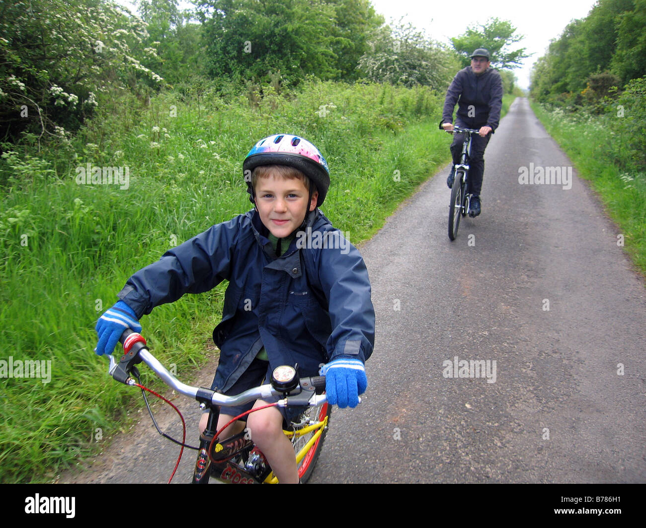 Les cycles d'un garçon le long d'un chemin de campagne avec son père PARUTION MODÈLE Banque D'Images