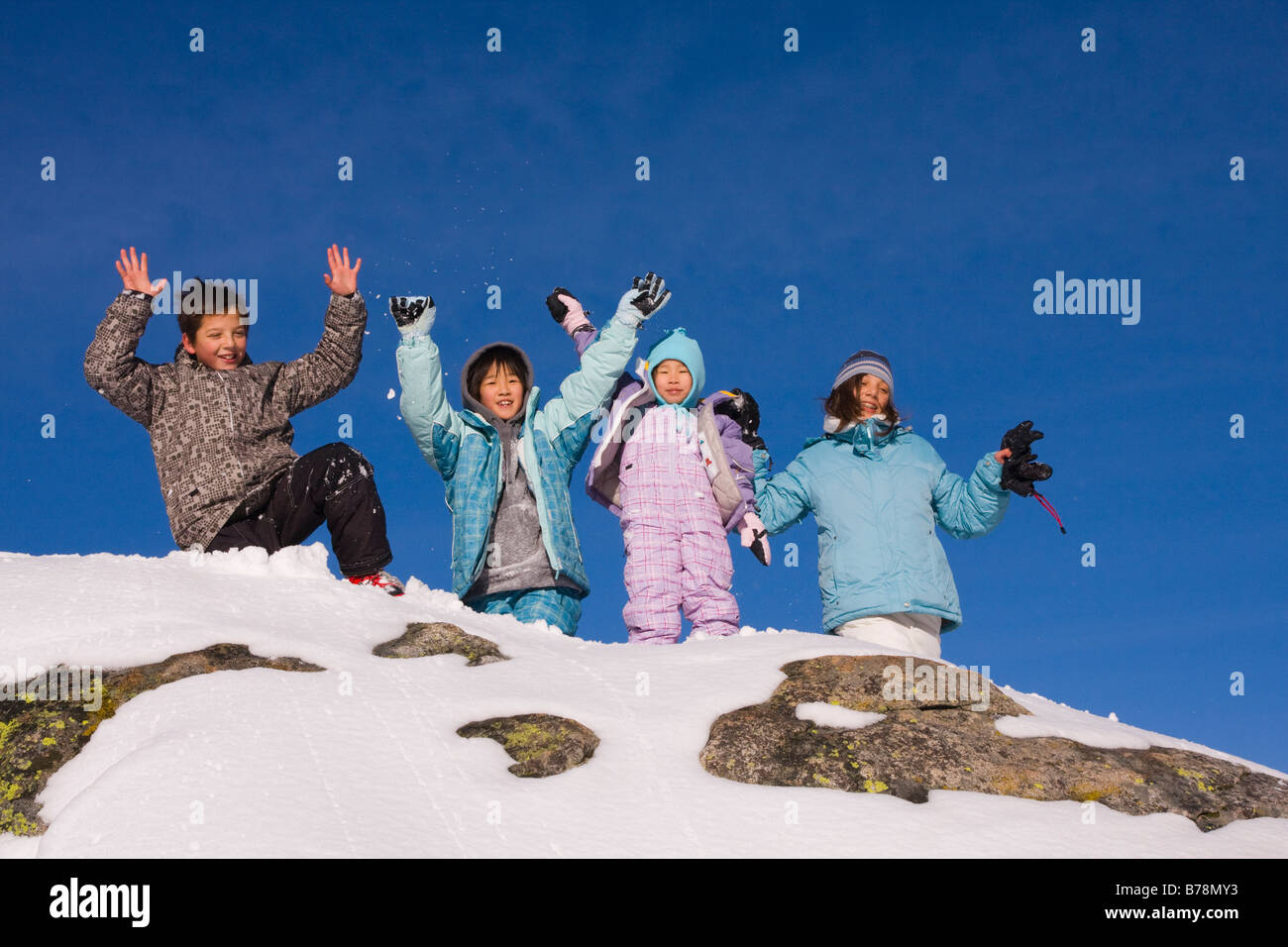 Quatre enfants se tenant sur le haut d'un rocher enneigé à Sierra à Tahoe ski resort, près du lac Tahoe en Californie Banque D'Images