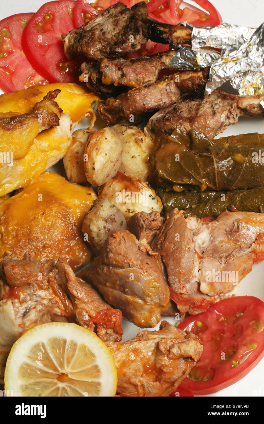 Plateau de style arabe d'agneau et de poulet cuit,les feuilles de vigne farcies, pommes de terre, côtelettes d'agneau grillées, de tomates et de citron. Banque D'Images