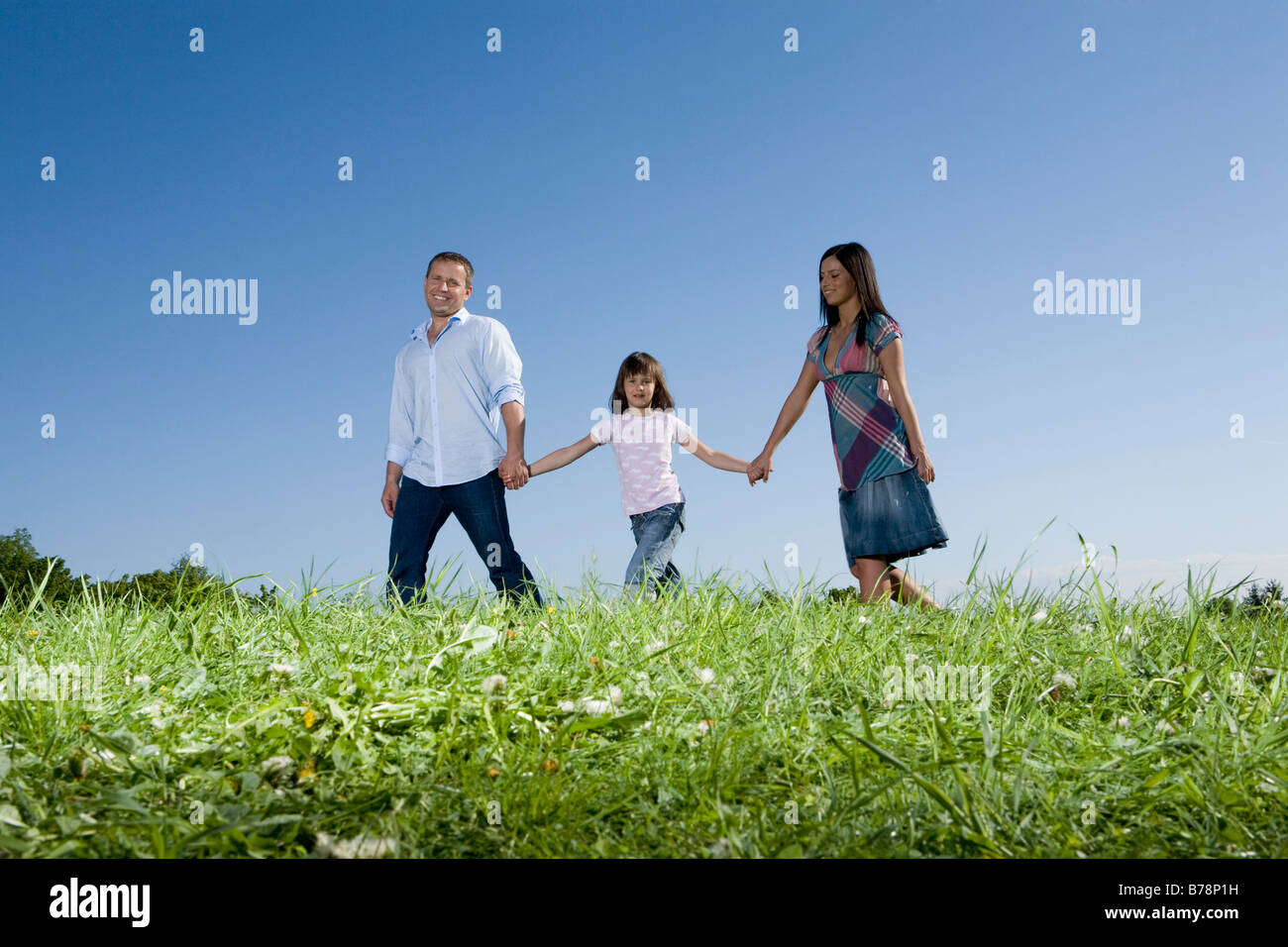 Les parents et la fille (6-7) de prendre une marche à travers prairie Banque D'Images