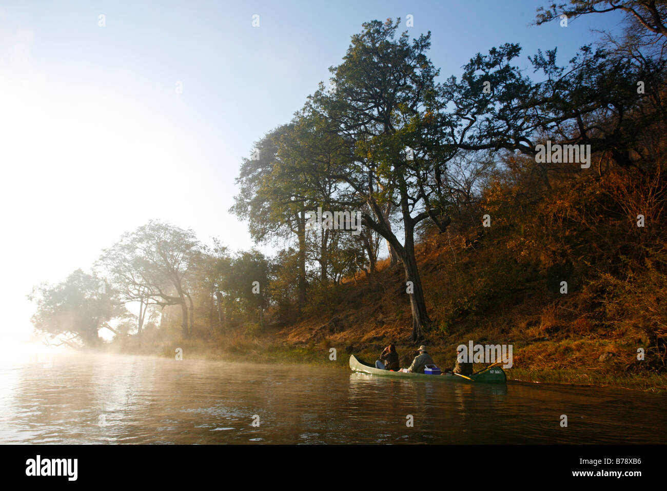 Un canot à fond plat le long de la rivière à la dérive sur le fleuve Zambèze à l'aube d'un matin brumeux Banque D'Images