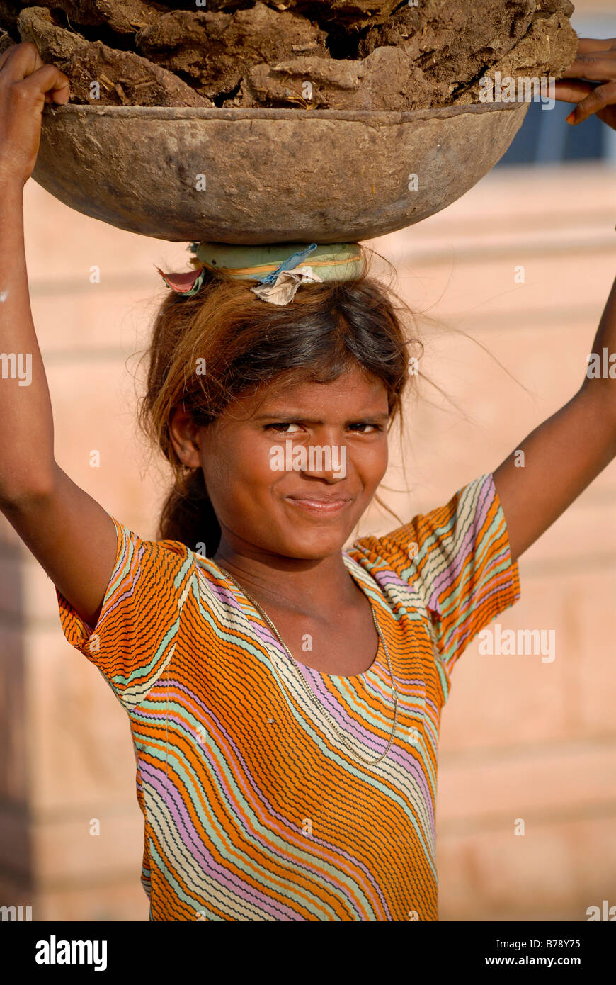 Fille portant un bol rempli avec de la bouse de vache sur sa tête, au Rajasthan, Pokahran au nord de l'Inde, l'Asie Banque D'Images