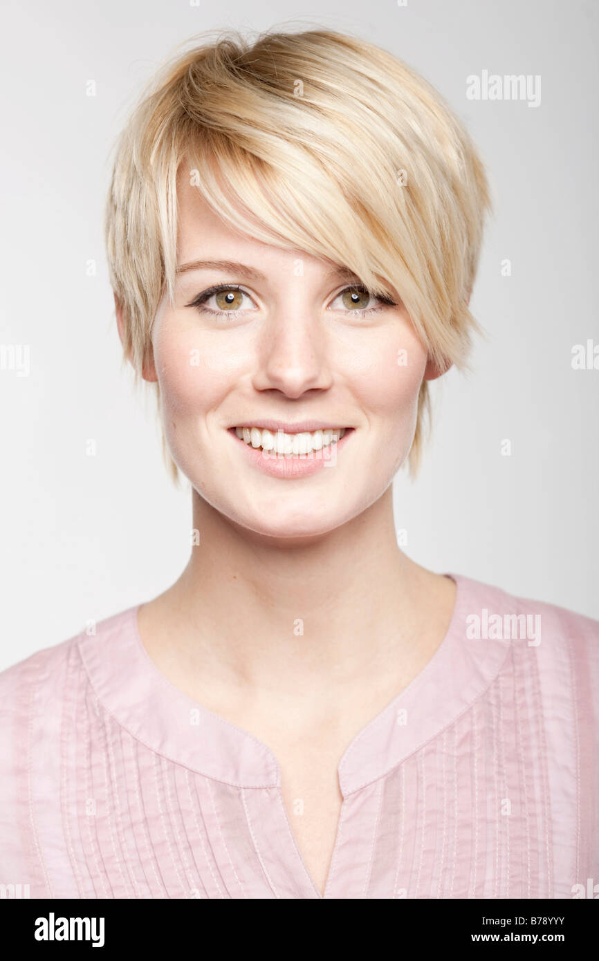 Jeune femme blonde aux cheveux courts en souriant à la caméra, de façon conviviale Banque D'Images