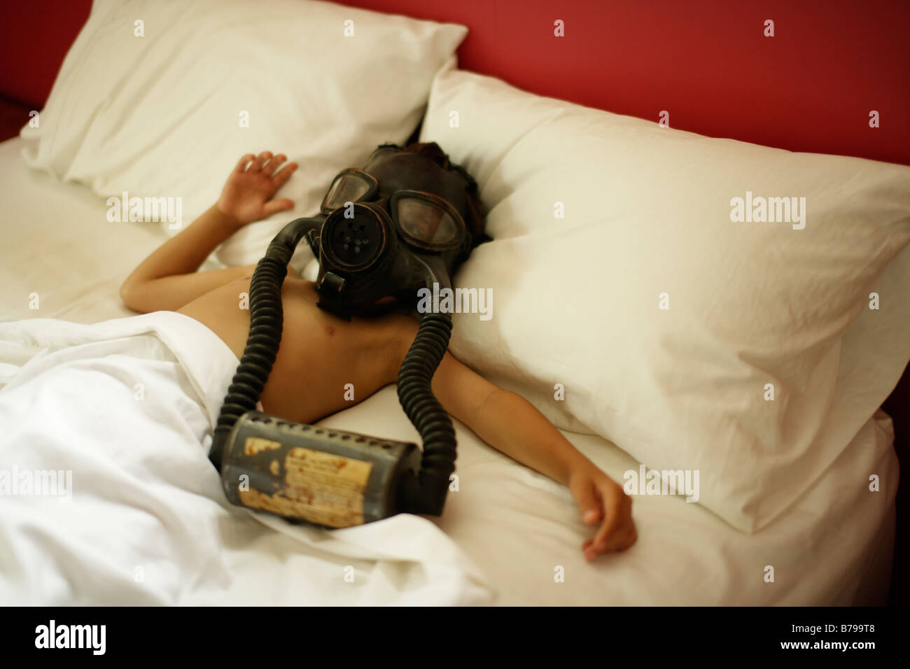 Un garçon de six ans se trouve dans le lit de porter le masque à gaz Banque D'Images