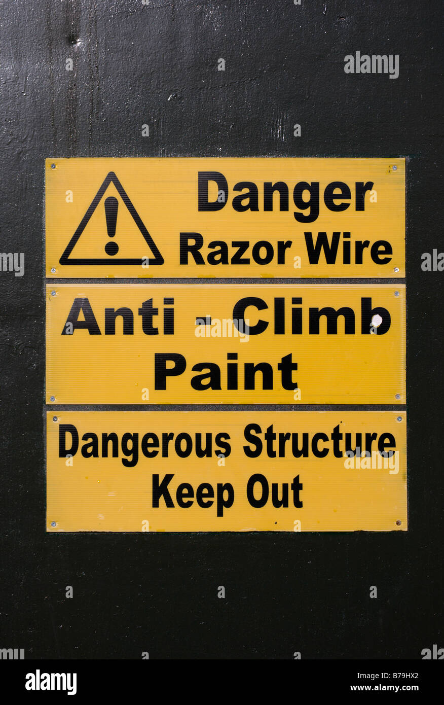 La jaune et noir sur le signe extérieur d'un bâtiment de structure d'avertissement dangereux, le fil barbelé, et anti-peinture montée Banque D'Images