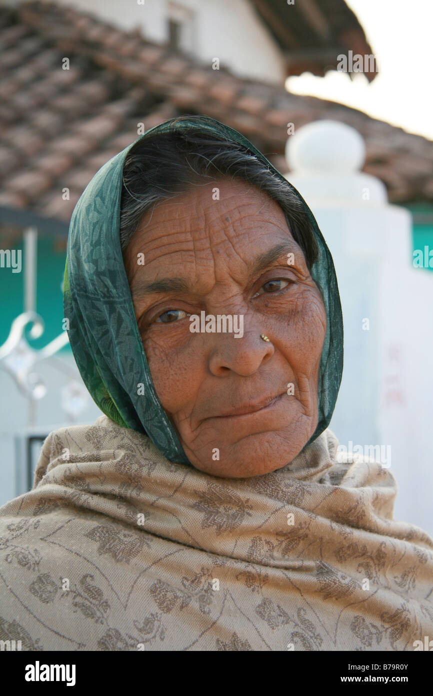 Une femme âgée portant un foulard vert à l'extérieur d'une maison verte et blanche dans le village de Moka, Madhya Pradesh, Inde Banque D'Images