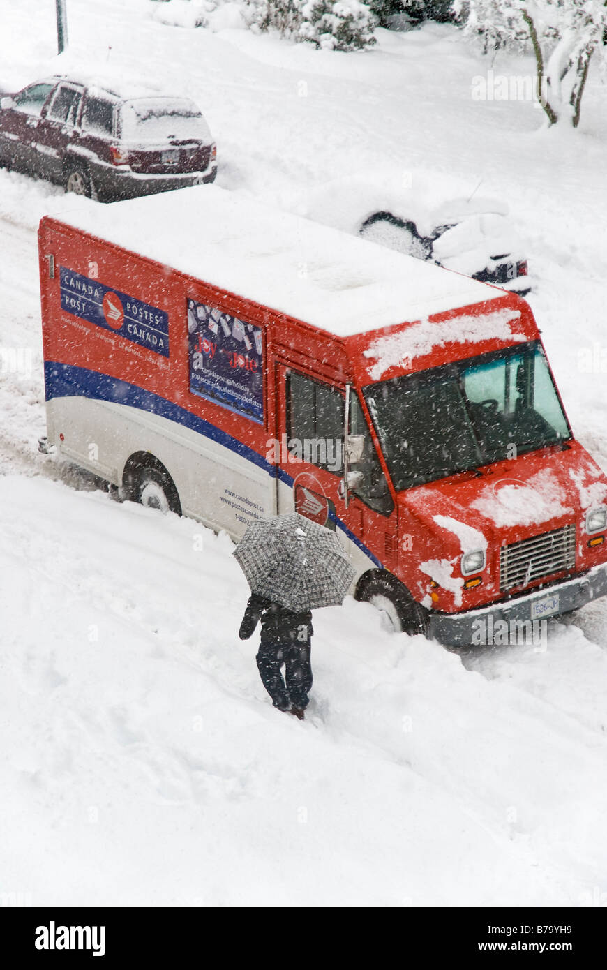 Le dirigeant d'une figure la marche et un camion de Postes Canada dans une forte tempête de neige. Banque D'Images