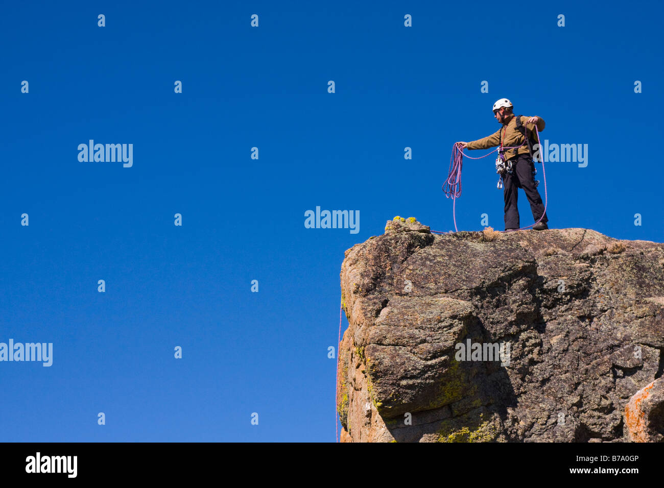 Un comité permanent de l'alpiniste au sommet d'une falaise enrouler sa corde Banque D'Images
