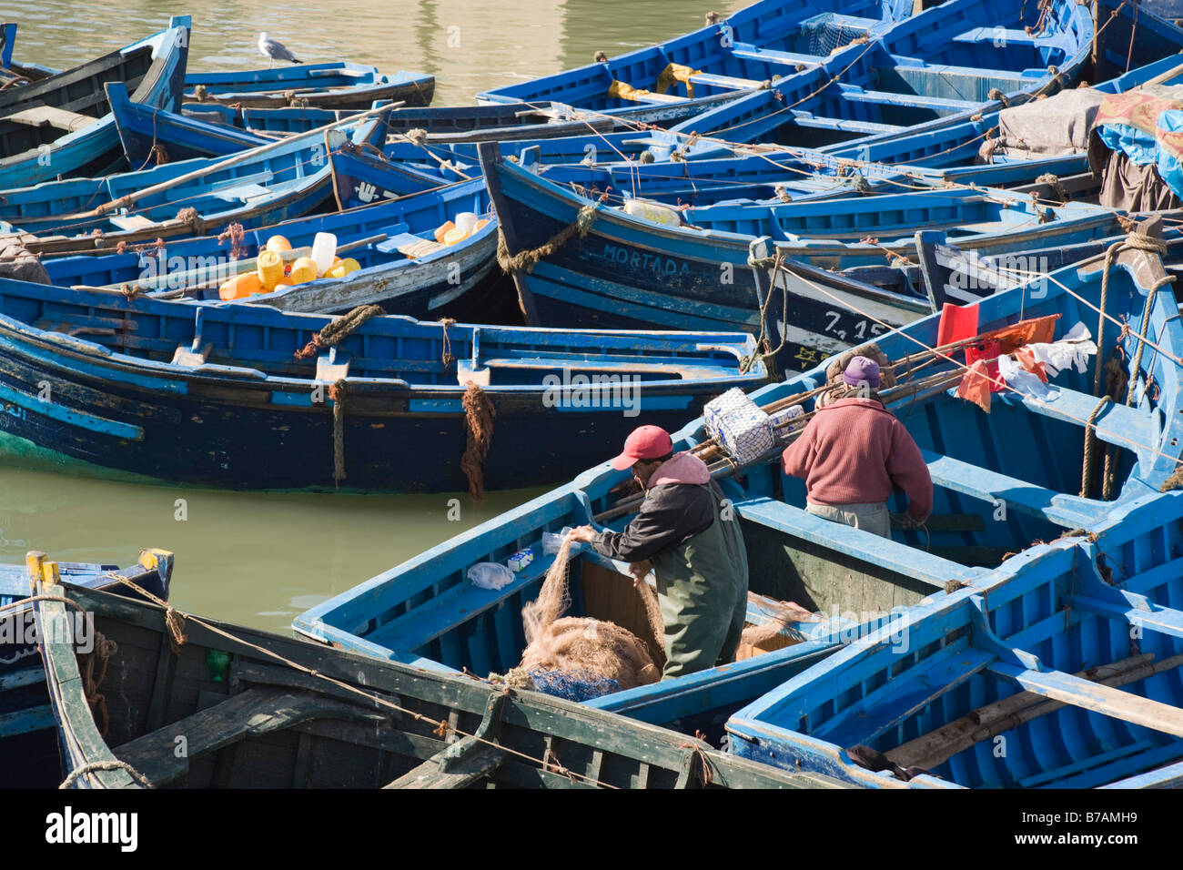 Essaouira Maroc Afrique du Nord Pêcheurs travaillant dans de petits bateaux de pêche en bois bleu à port sur la côte ouest Banque D'Images