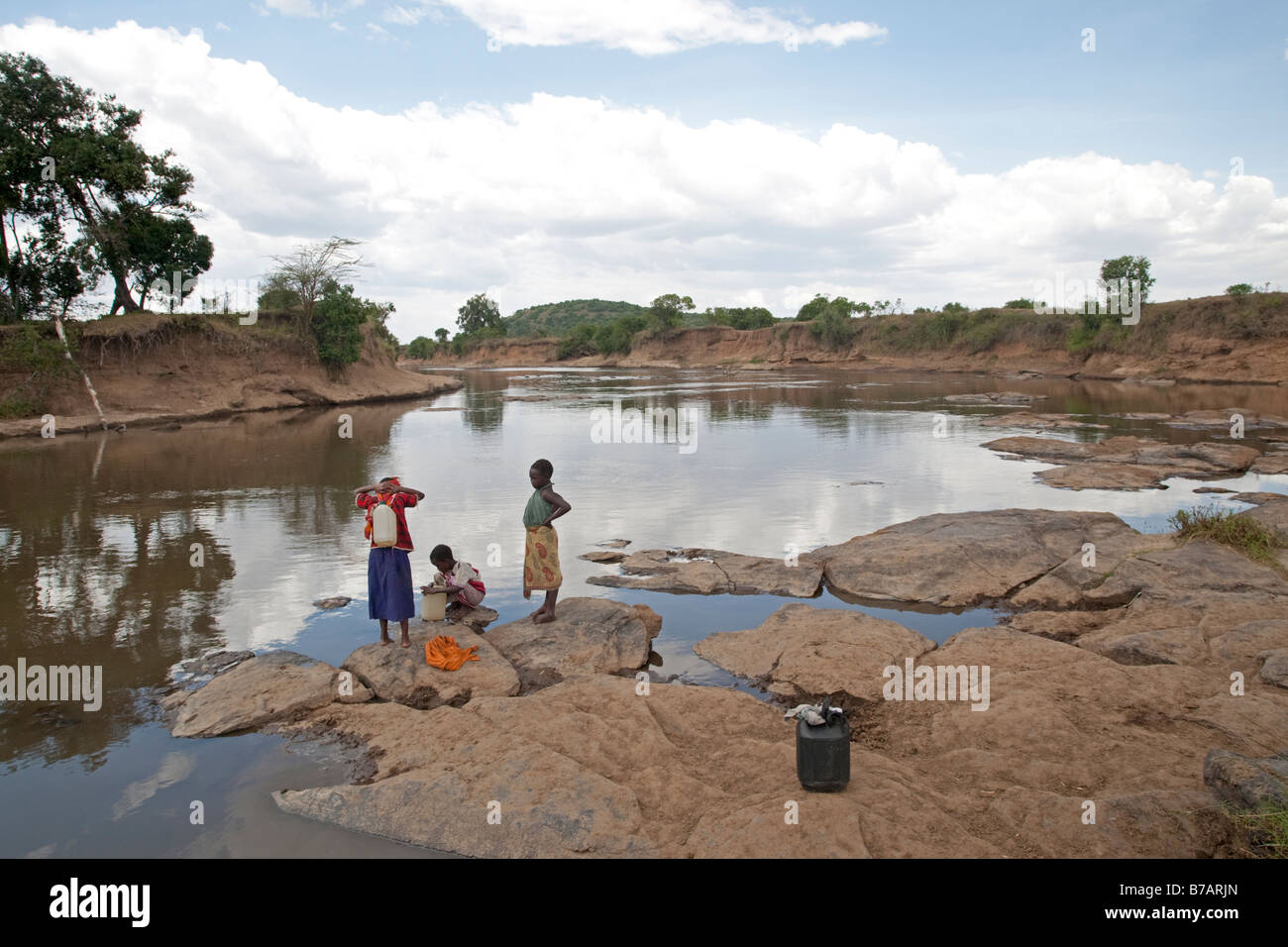 La collecte de l'eau enfants Masai Mara River North réserve de Masai Mara au Kenya Banque D'Images