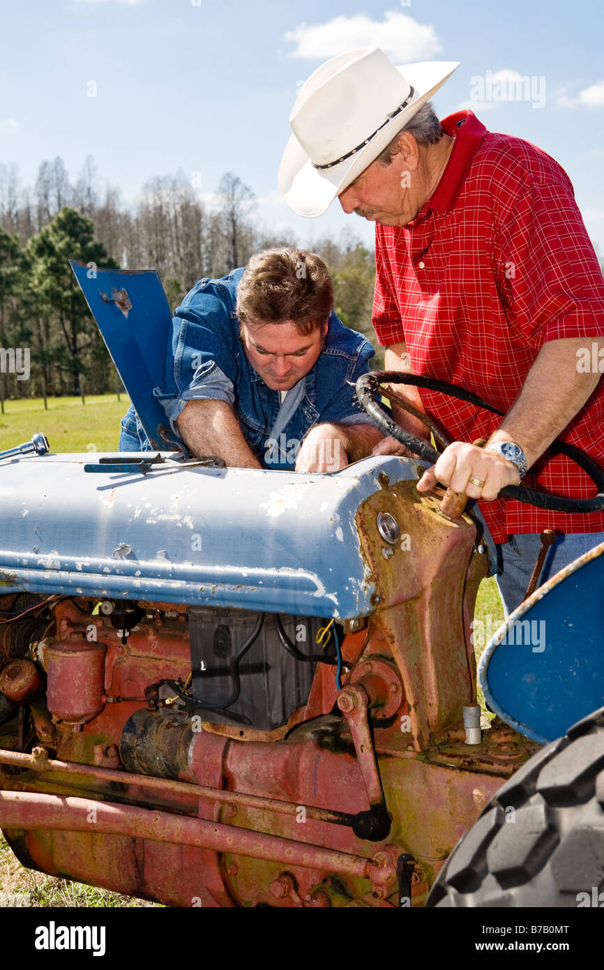 Ranch de la réparation d'un tracteur comme l'éleveur supervise Banque D'Images