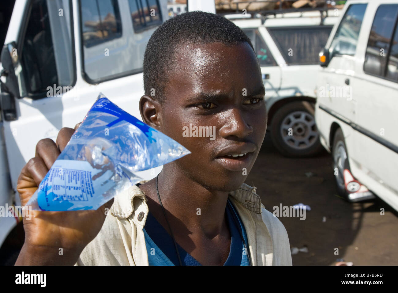 Jeune homme vendant de l'eau potable à la station de bus ou à la Gare Routière Pompiers à Dakar au Sénégal Banque D'Images