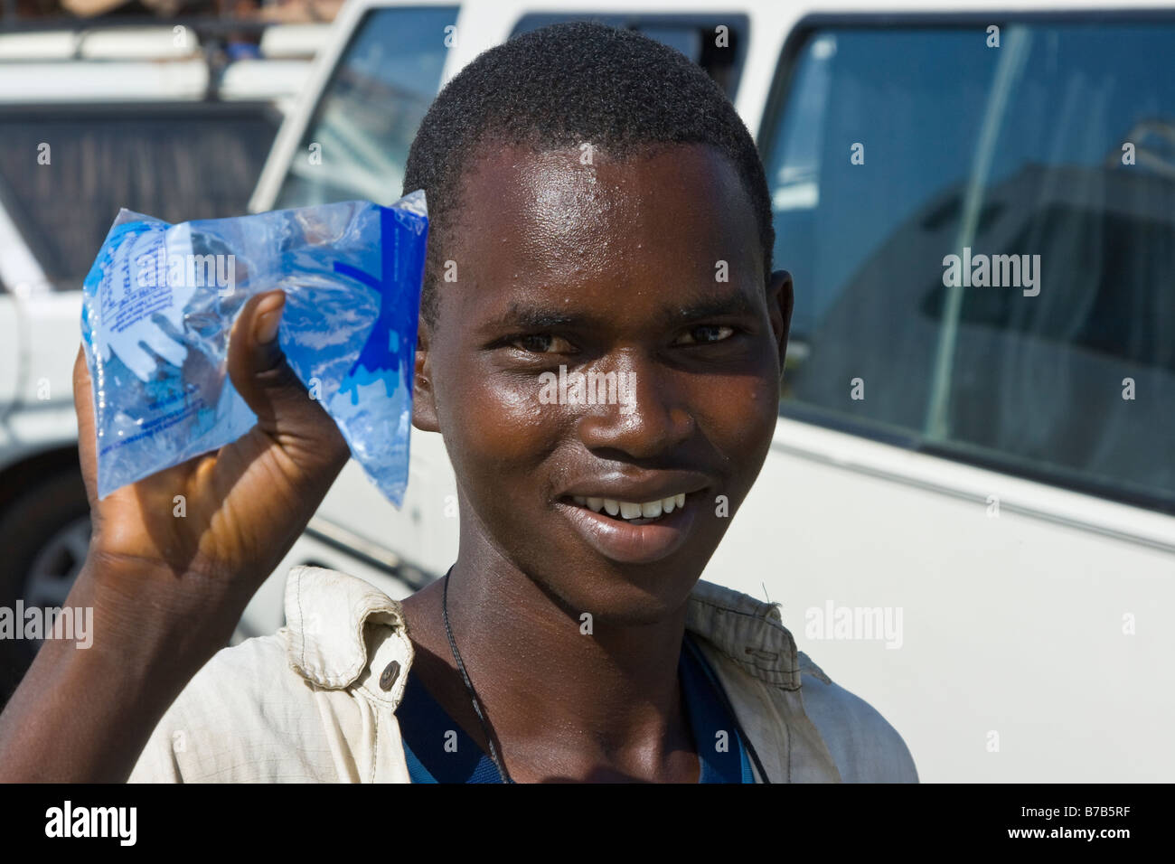 Jeune homme vendant de l'eau potable à la station de bus ou à la Gare Routière Pompiers à Dakar au Sénégal Banque D'Images