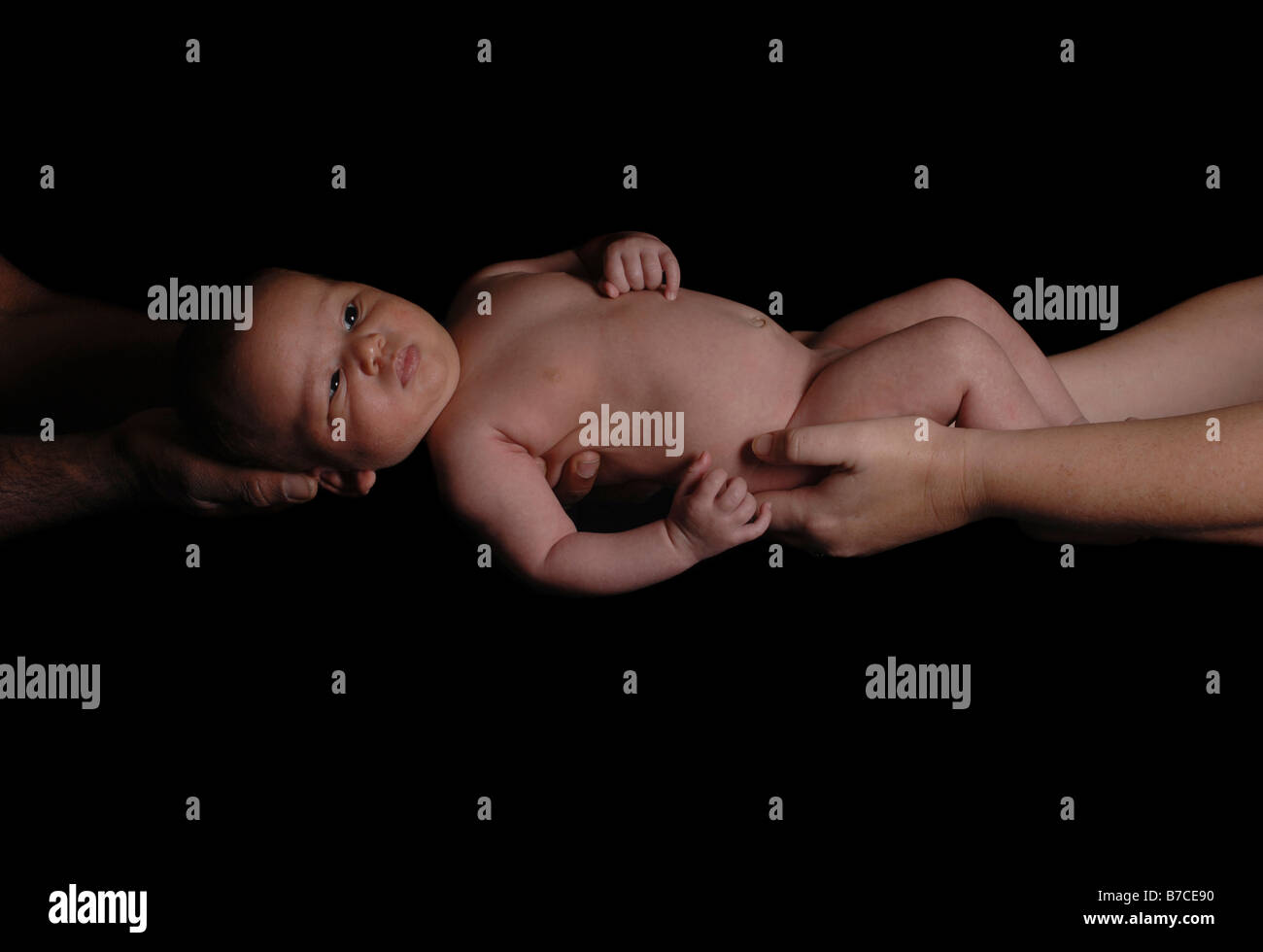 Un bébé de quatre mois garçon tenu par sa maman et papa noir blanc Banque D'Images