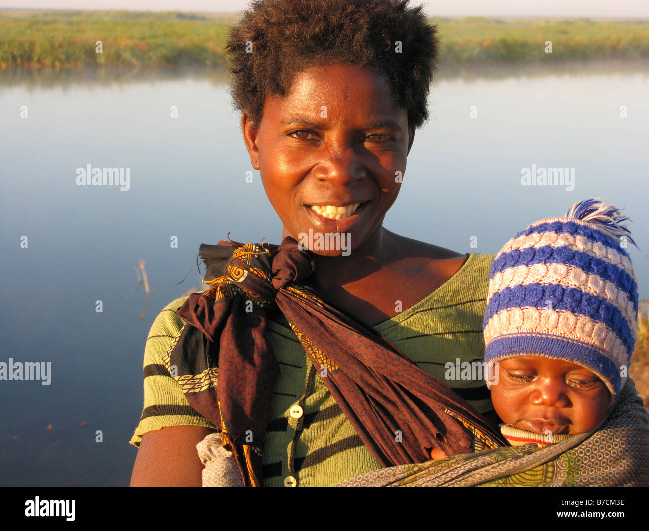 Femme de la tribu Bemba avec bébé la vente de charbon de bois sur la rivière Luapula ou Congo sur la banque de Zambie En Zambie district Milenge Banque D'Images