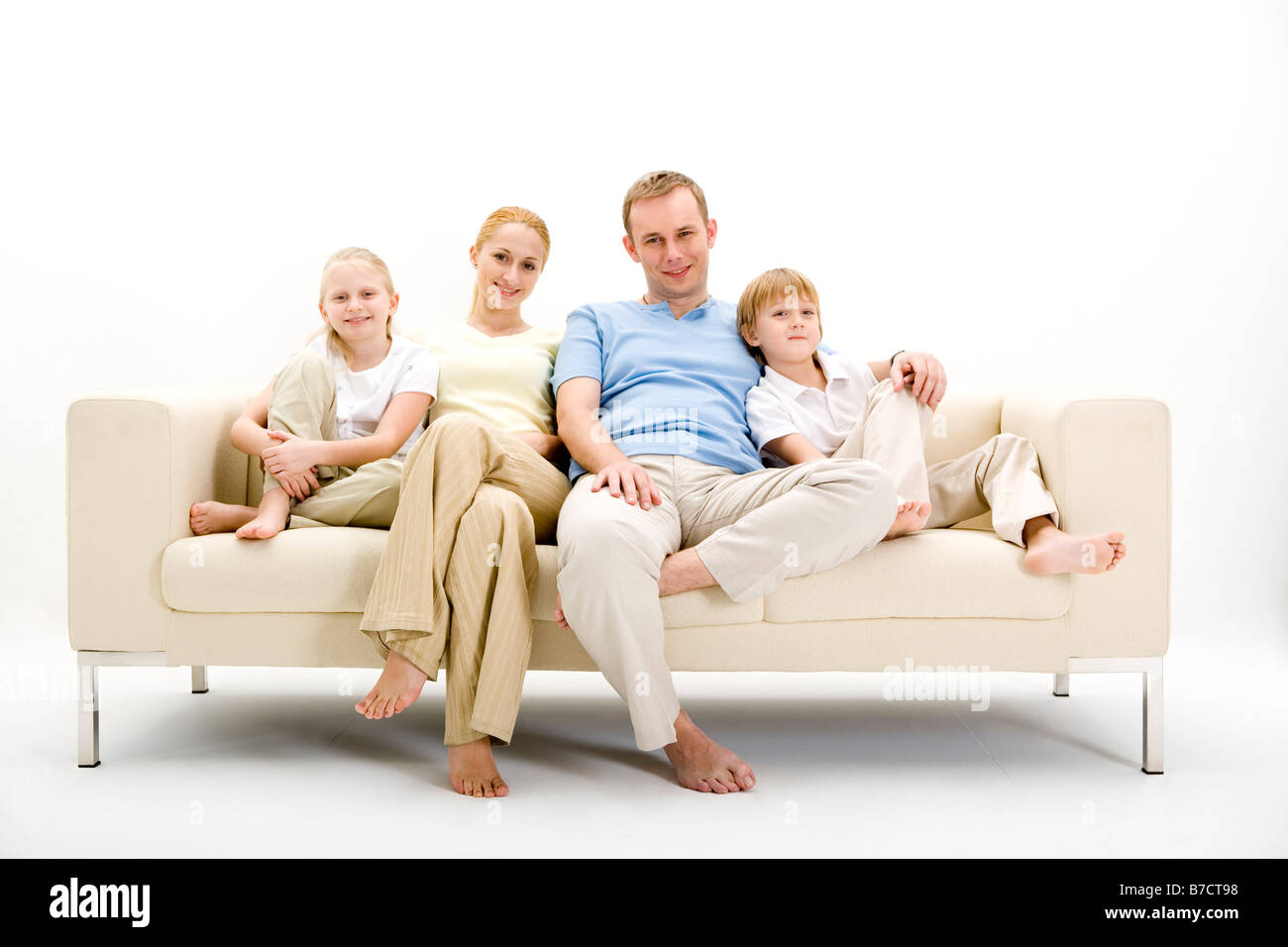 Portrait of family sitting on sofa smiling Banque D'Images