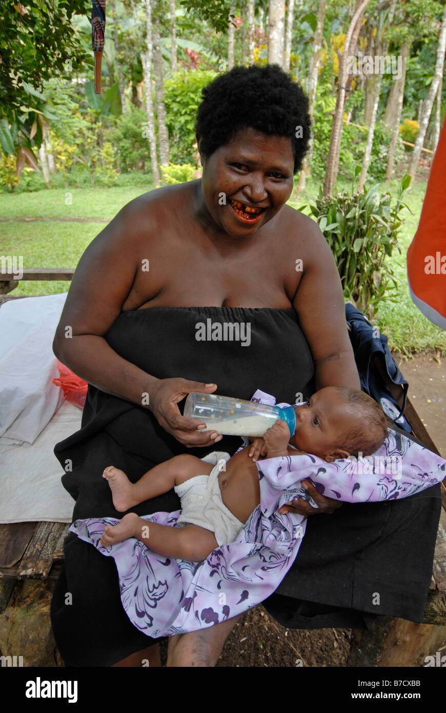 Mère locale avec la bouche rouge en raison de bétel mâchant, nourrir son bébé. Banque D'Images